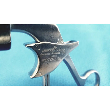 Silver metallic firearm trigger with engraved markings on the back of Jarit 610-140 roto-lok stainless steel clamp steel clamp