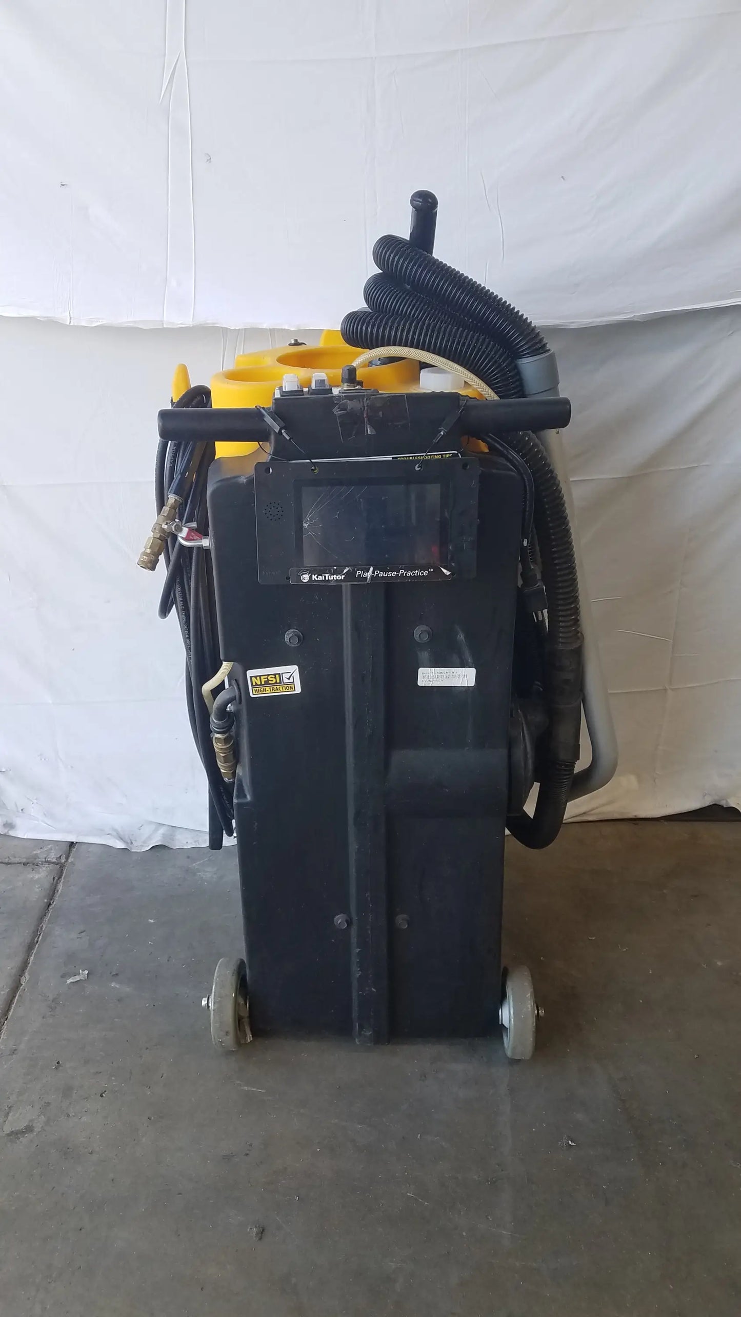 Black kaivac wet dry vacuum cleaning system with yellow accents and coiled hoses for industrial floor cleaning