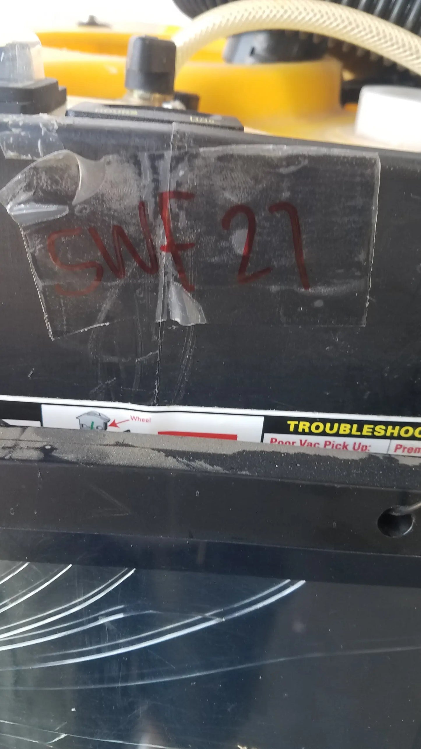 Black plastic component with red markings and transparent tape on the back side of kaivac wet dry vacuum system