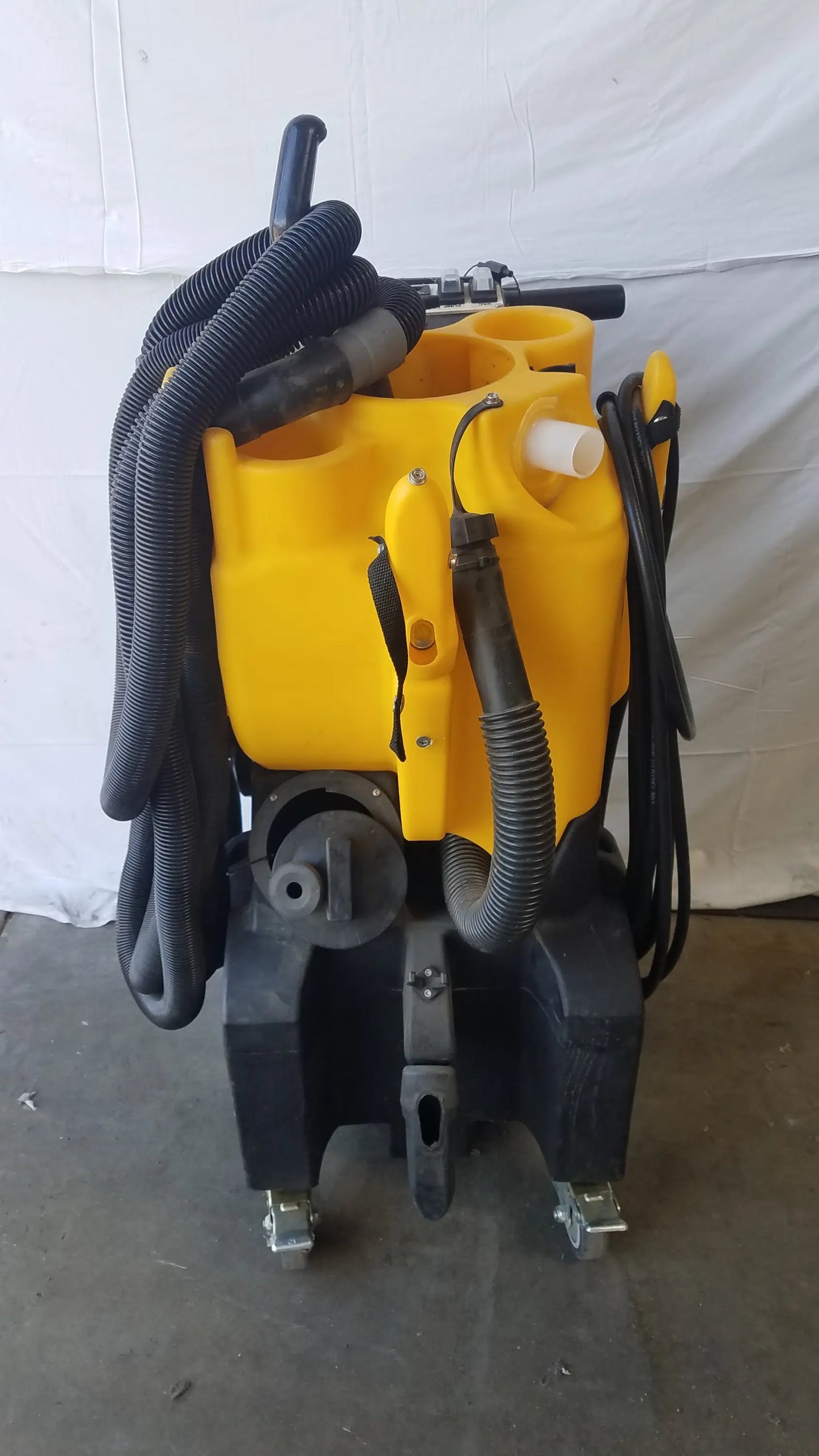 Yellow and black Kaivac wet dry vacuum cleaning system with coiled hoses and wheels for industrial floor cleaning