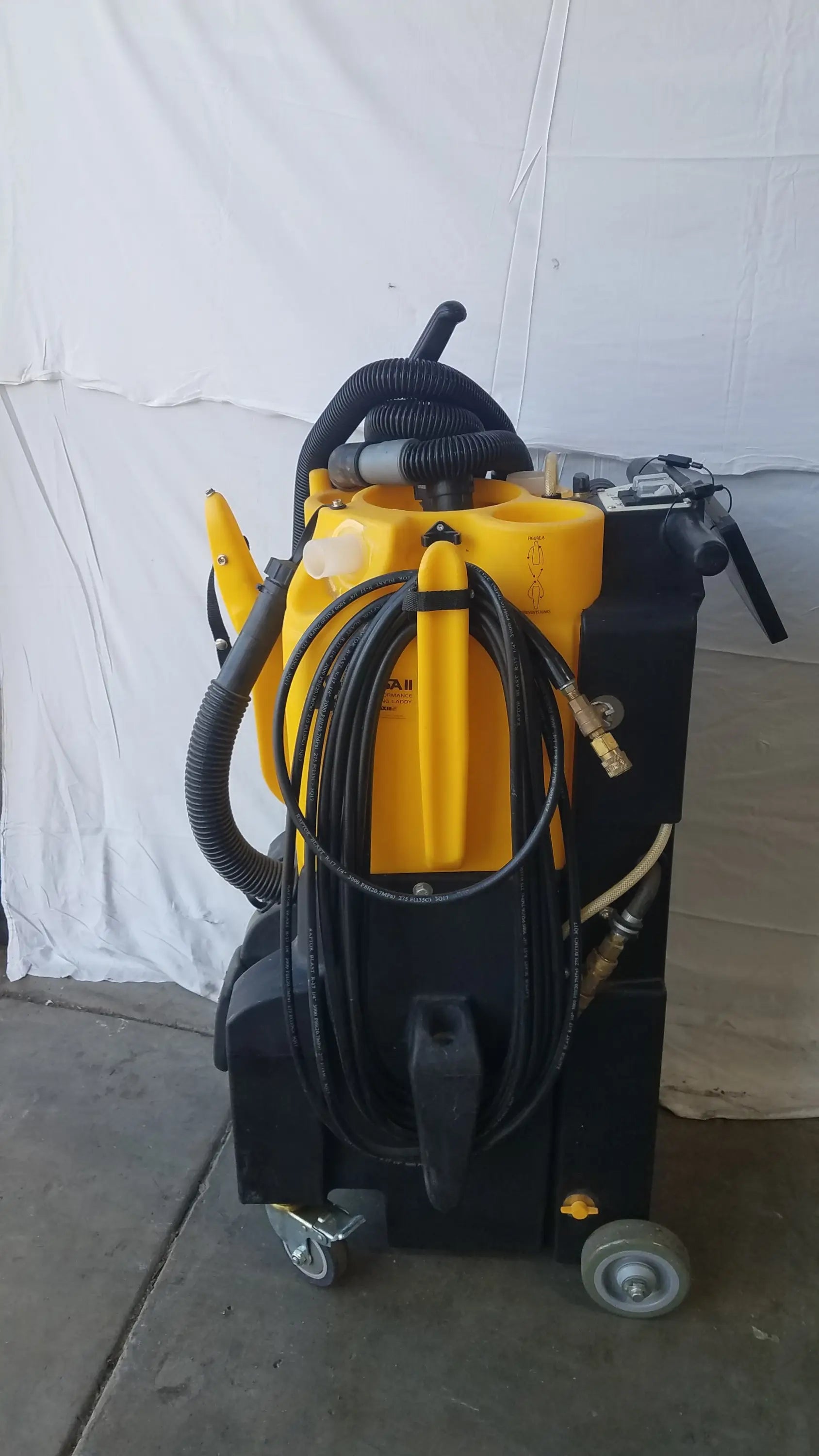 Yellow and black kaivac wet dry vacuum cleaning system with coiled hoses and wheels for industrial floor cleaning