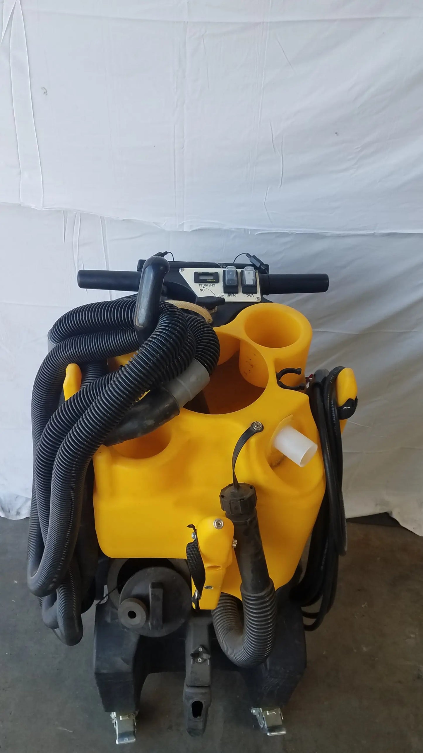 Yellow kaivac wet dry vacuum cleaning system with black hoses and handle for industrial floor cleaning