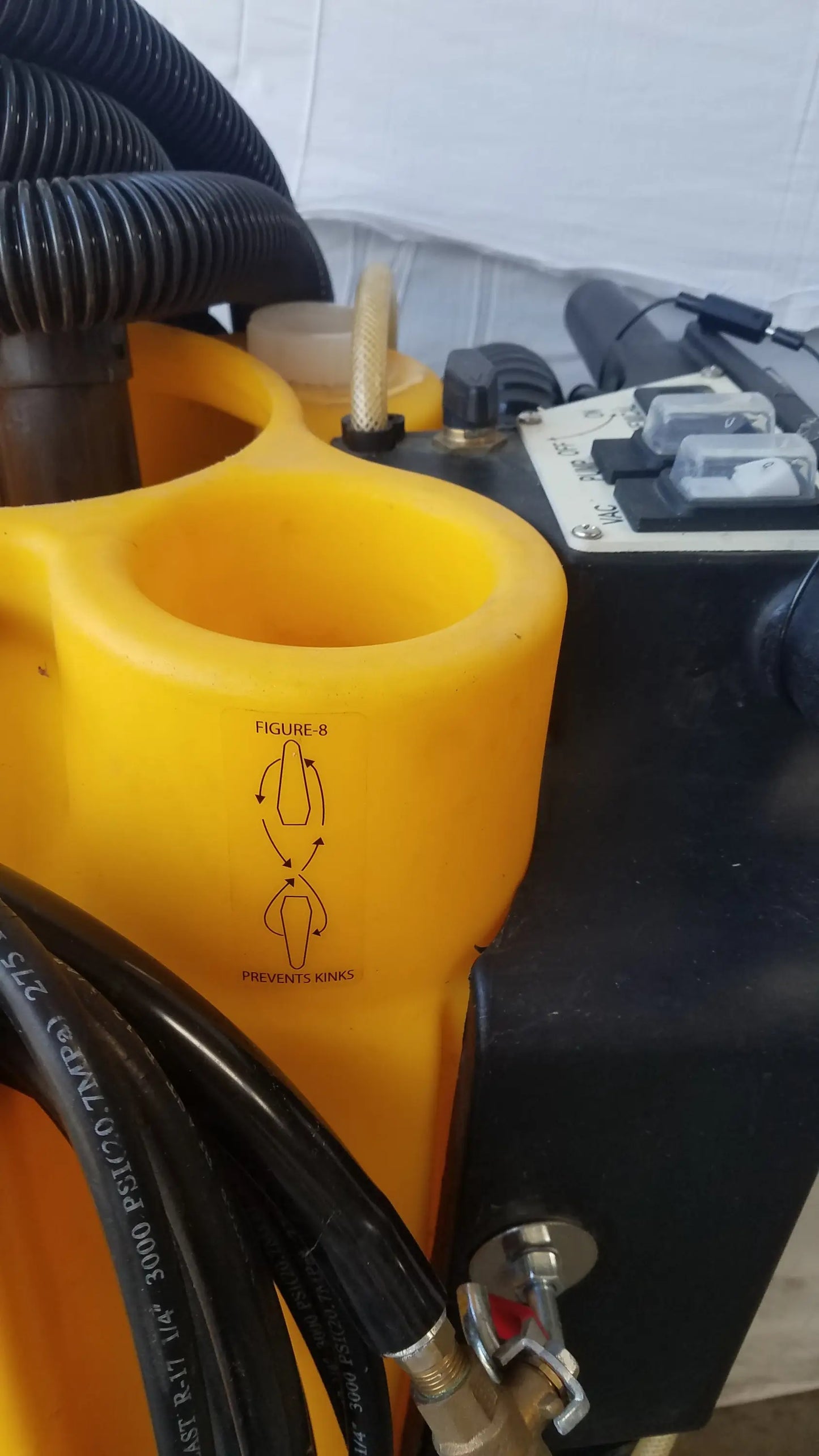 Yellow plastic component with black corrugated hoses and metal fittings of Kaivac wet dry vacuum cleaning system back side