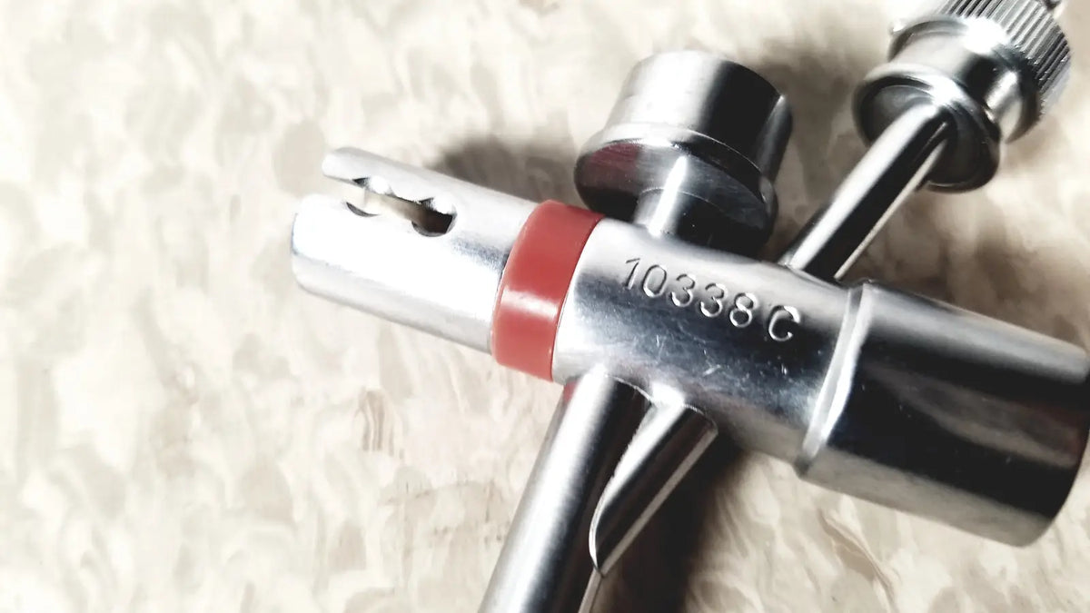 Silver multi-tool tire inflator with red rubber band and engraved model number shown with karl storz 10338c surgical bronchoscope sheath