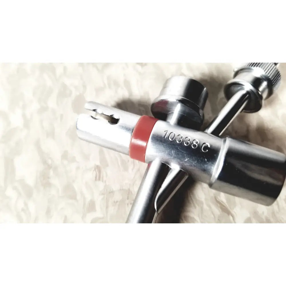 Silver multi-tool tire inflator with red rubber band and engraved model number shown with karl storz 10338c surgical bronchoscope sheath
