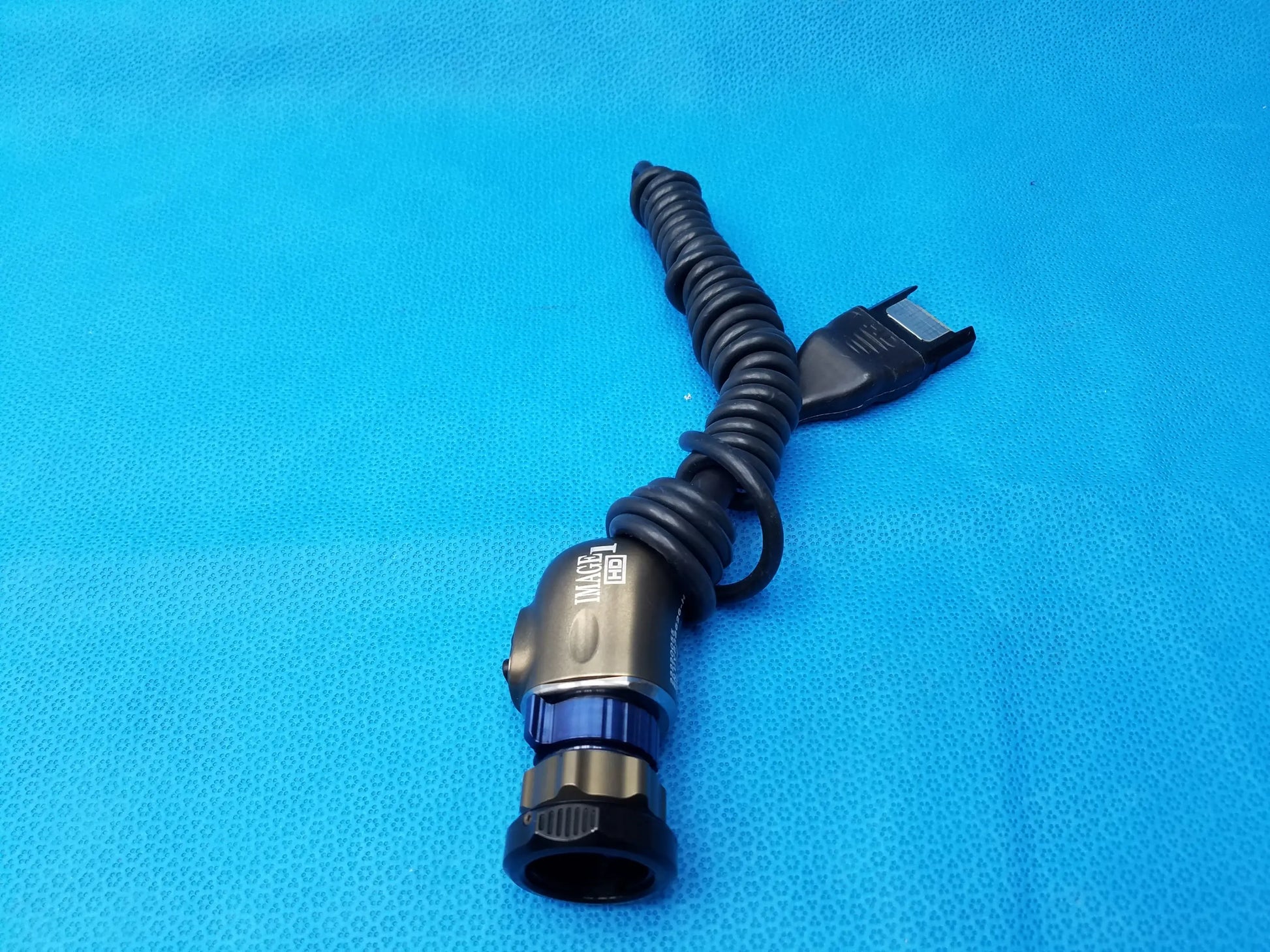 Black coiled karl storz camera head cable with metallic connector and blue accent ring precision imaging component
