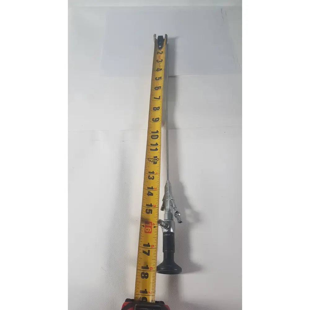 Silver karl storz 27410 sk 7.5fr autoclavable rigid scope dual channel with black grip and articulated joints alongside yellow measuring tape