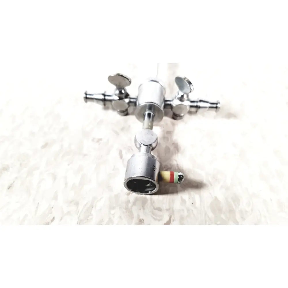 Silver-colored metal storz 28124cr cannula with dual rotating stopcocks and a gauge marked in red green and yellow stripes