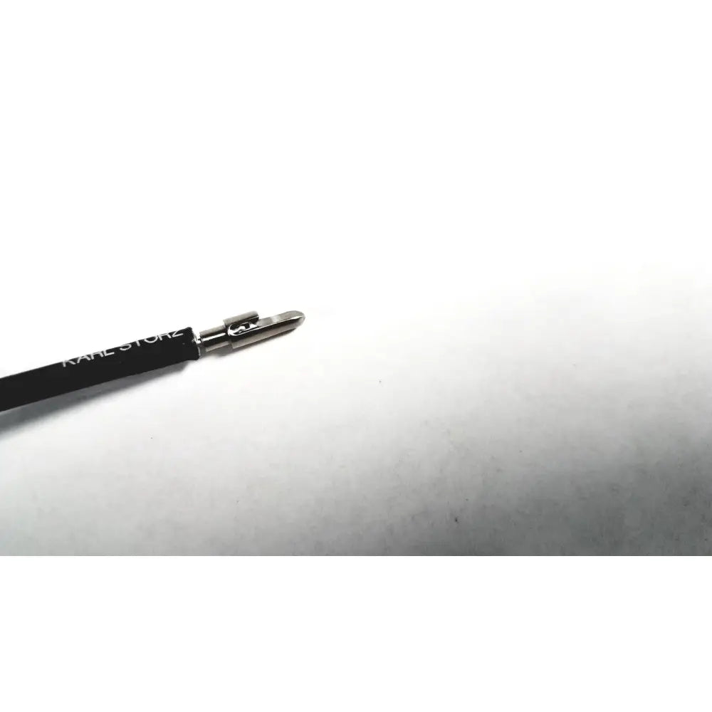 Black karl lagerfeld eyeliner pencil with silver metallic tip and logo alongside karl storz shaft laparoscopic grasper tool
