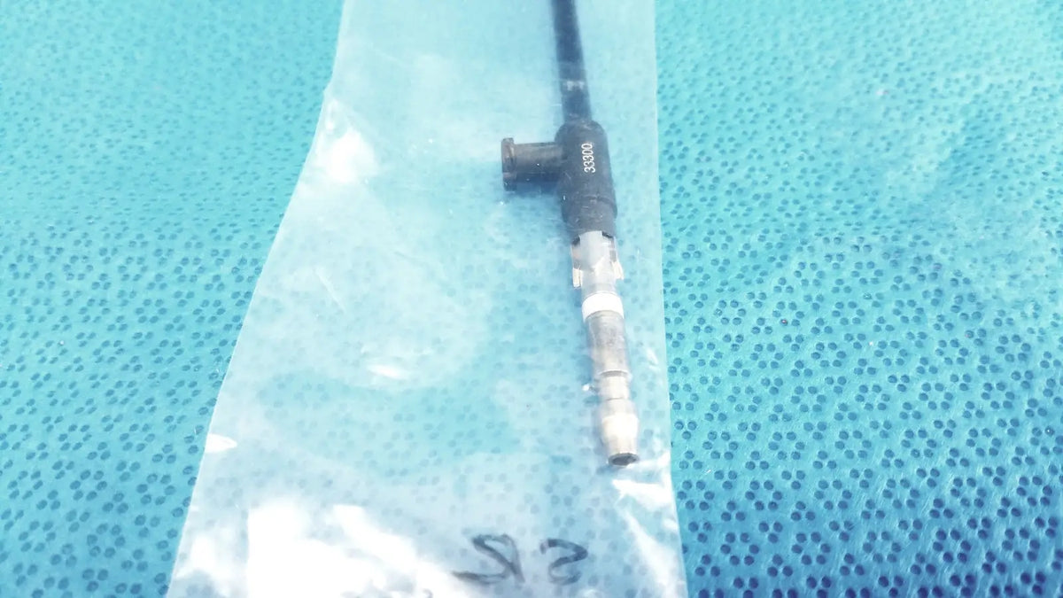 Black karl storz insulated outer tube catheter with metallic connector and printed markings resting in clear plastic bag