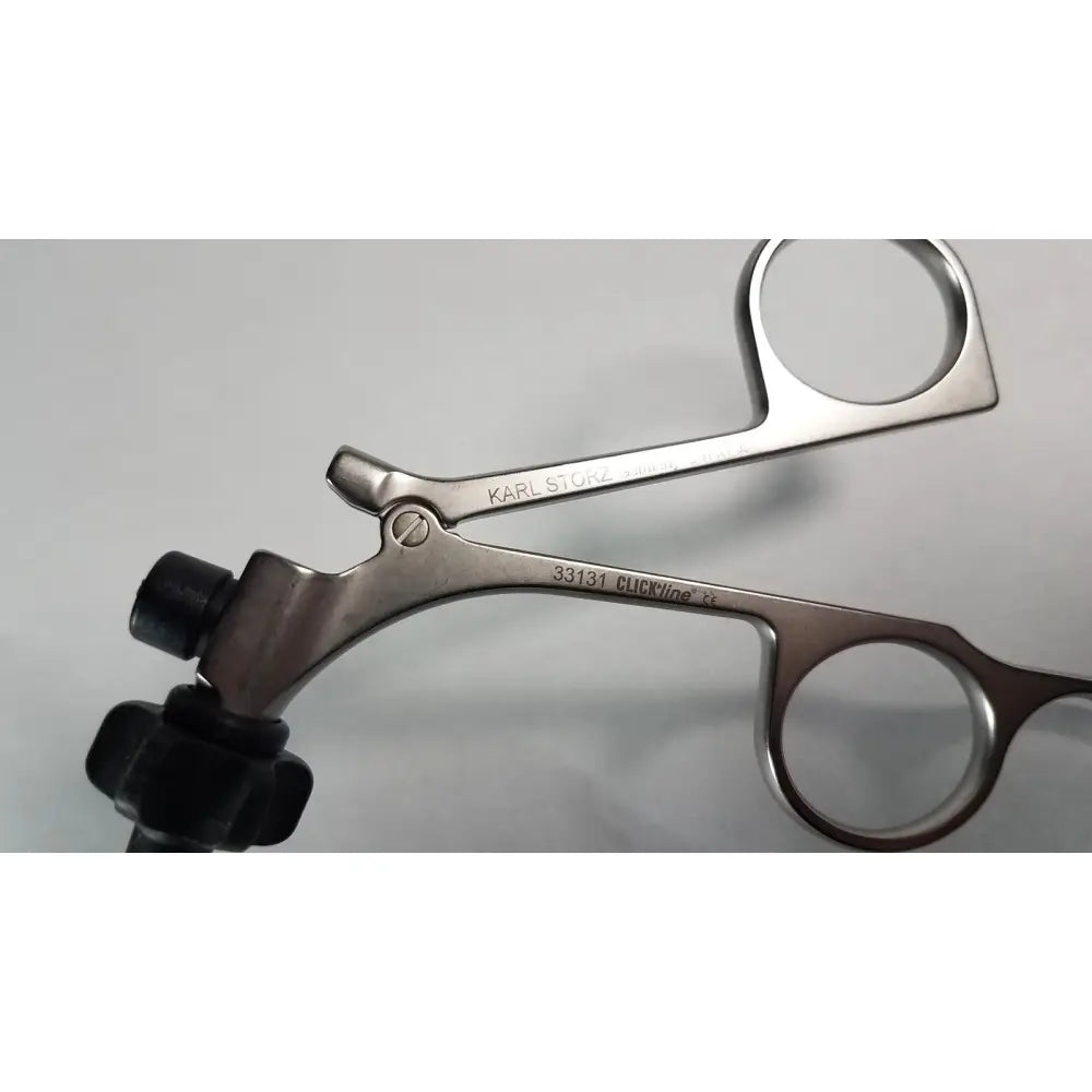 Silver surgical forceps with black rubberized handles branded karl storz clickline model 33131 for medical use