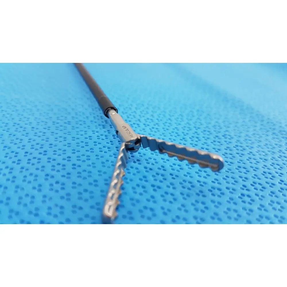 Silver surgical instrument with black handle and serrated cross-shaped tips in karl storz laparoscopic sheath model 33400