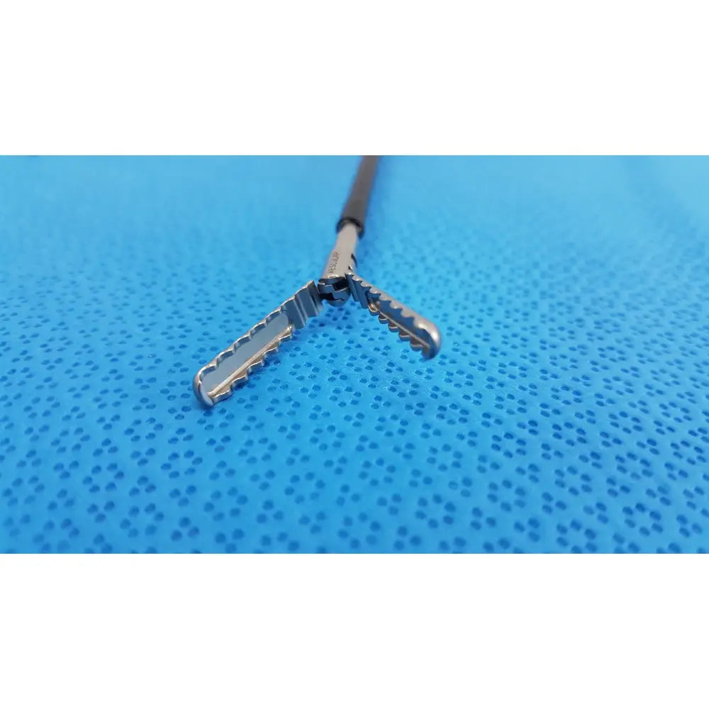 Silver karl storz laparoscopic sheath model 33400 with textured serrated jaws and black handle for surgical use