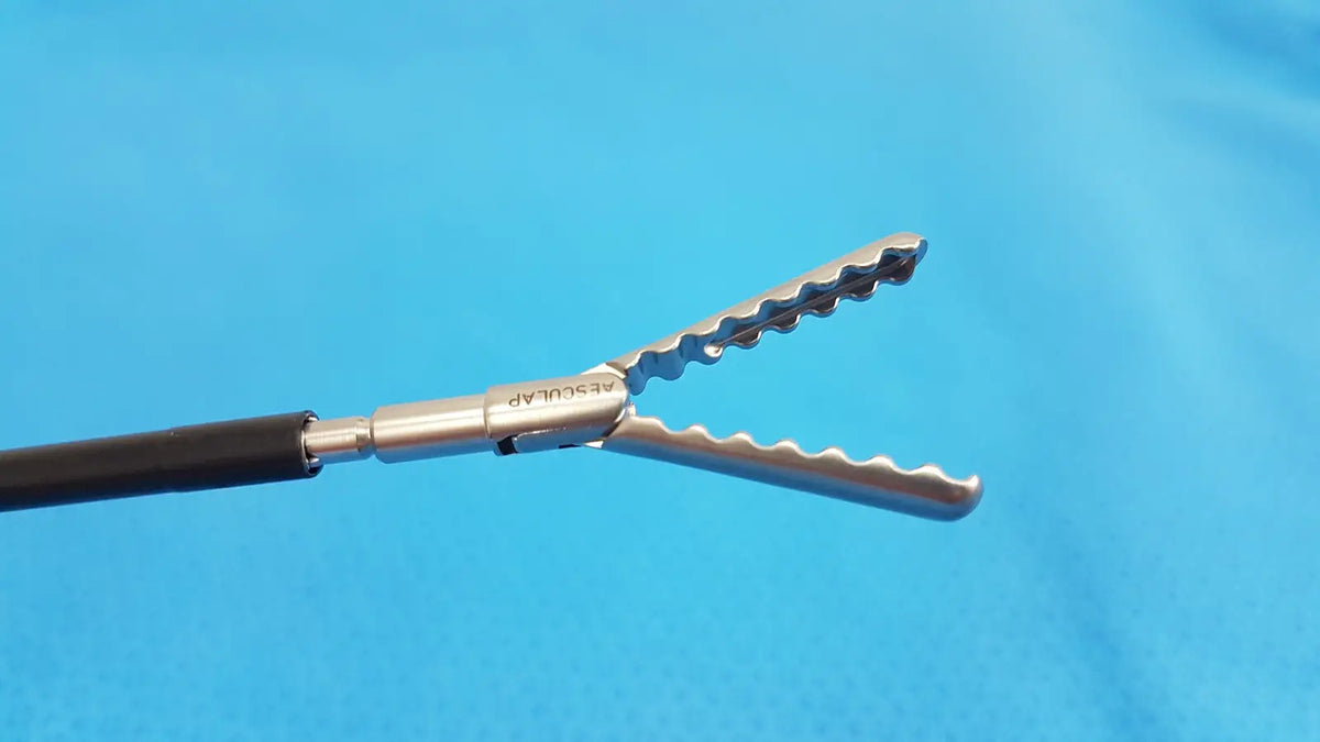 Silver surgical forceps with serrated wavy jaws and black handle in karl storz laparoscopic sheath model 33400