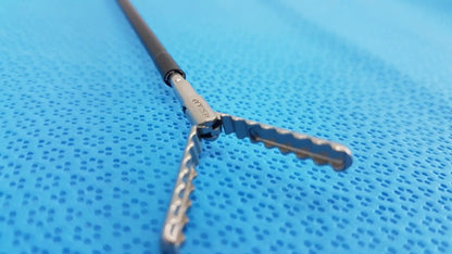 Silver surgical instrument with black handle and serrated cross-shaped tips in karl storz laparoscopic sheath model 33400
