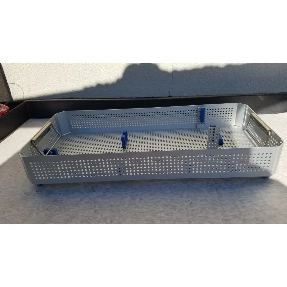 Silver perforated metal karl storz sterilization container case with blue plastic clamps for surgical instruments