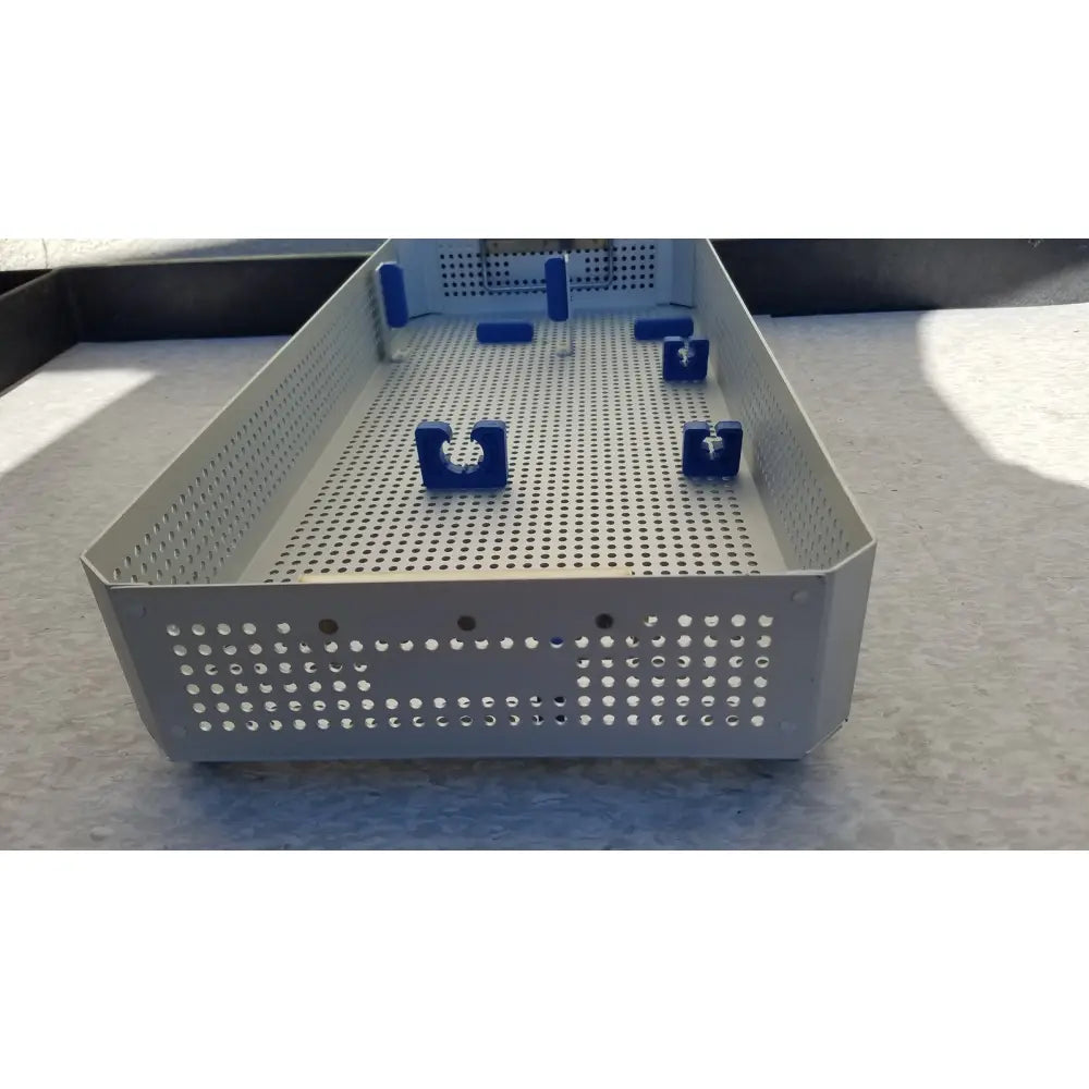 Gray perforated metal karl storz sterilization container case with blue plastic clamps for surgical instruments