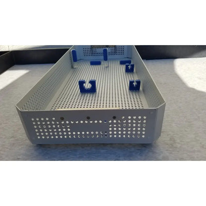 Gray perforated metal karl storz sterilization container case with blue plastic clamps for surgical instruments