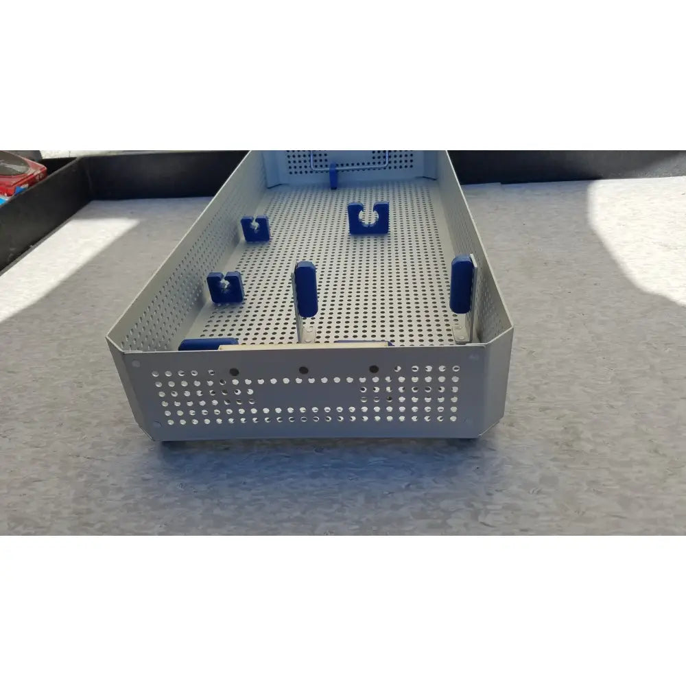 Silver perforated metal surgical instrument tray with blue handles and clamps in karl storz sterilization container case