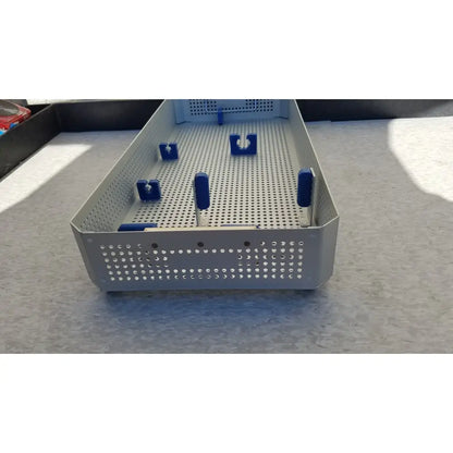 Silver perforated metal surgical instrument tray with blue handles and clamps in karl storz sterilization container case