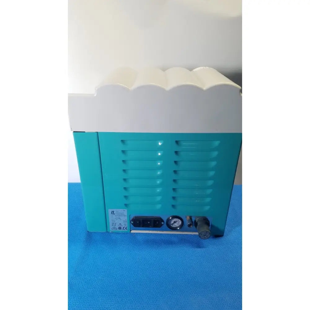 Teal and white kavo quattrocare 2104a dental handpiece maintenance unit with scalloped top edge and pressure gauge