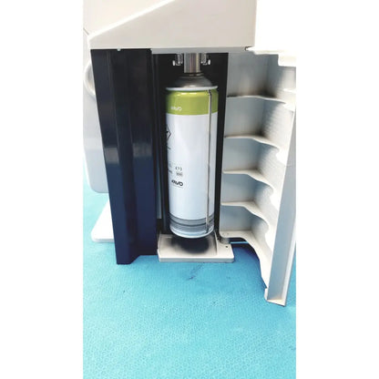 A white and green kavo quattrocare plus spray can with metallic nozzle inside the machine compartment for handpiece maintenance