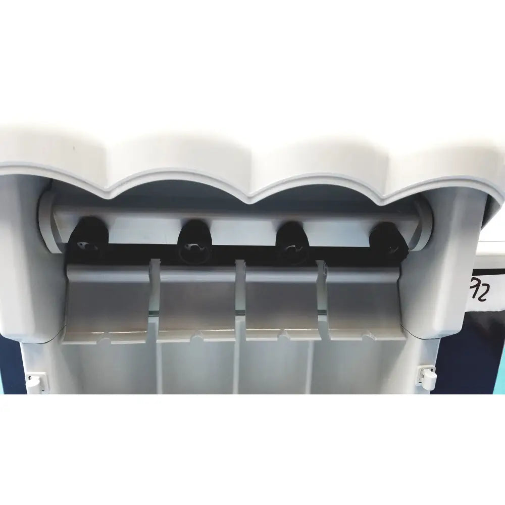 White plastic kavo quattrocare plus 2124 a handpiece maintenance system with black dispensing nozzles and scalloped top edge