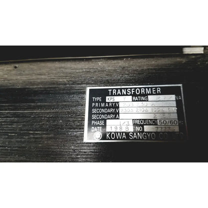 Silver metallic label on a dark surface showing technical specifications for kowa sangyo power transformers reuse medical product