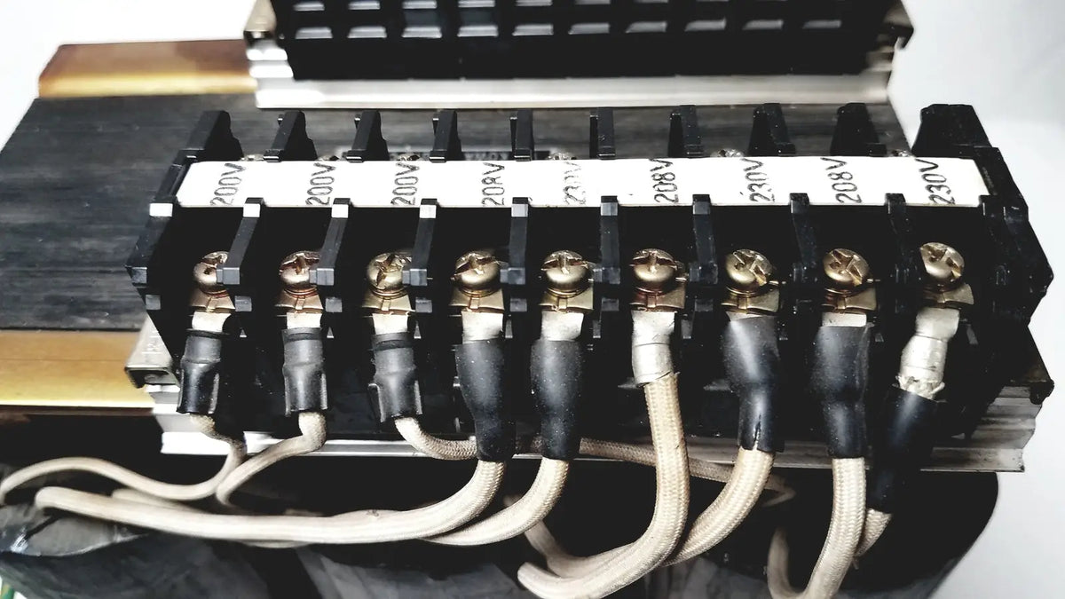 Black electrical terminal block with gold screws and labeled insulators for 208v connected to kowa sangyo power transformers