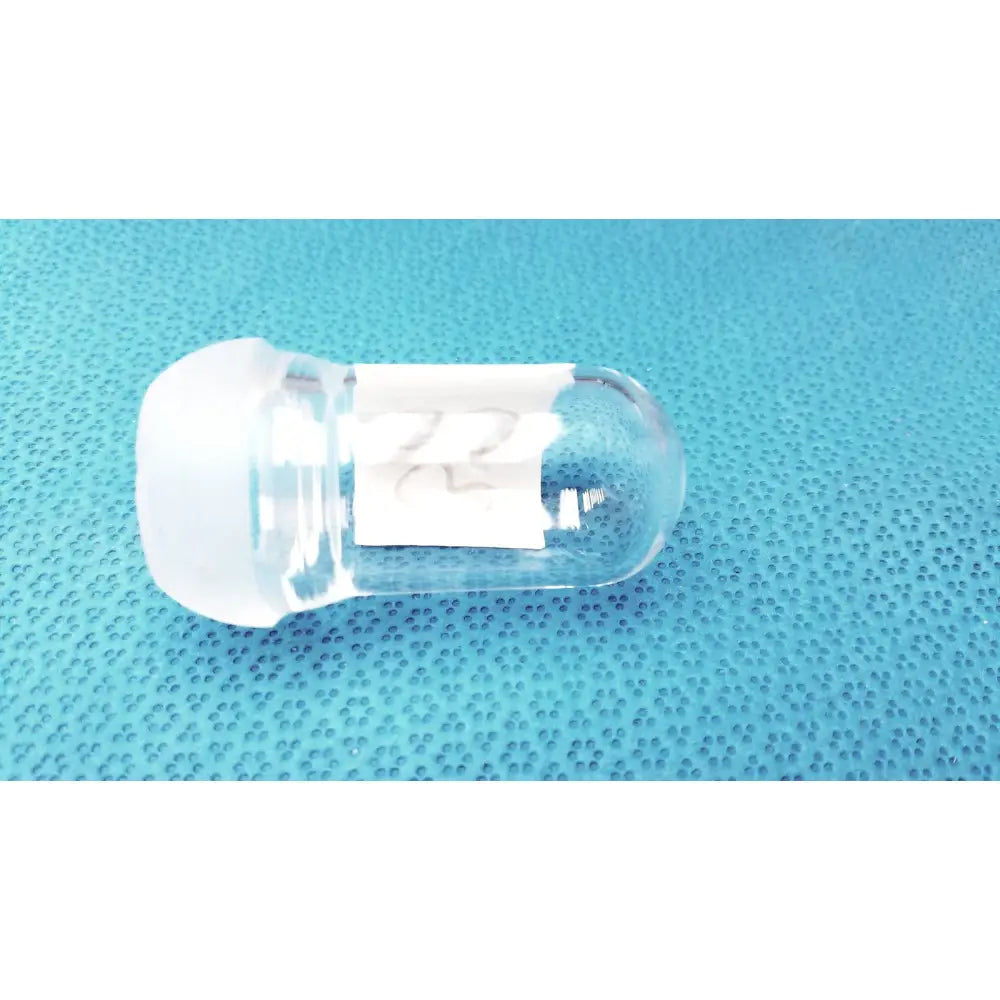 Clear glass lab spherical joint stopper with frosted white cap and small white label affixed to the side