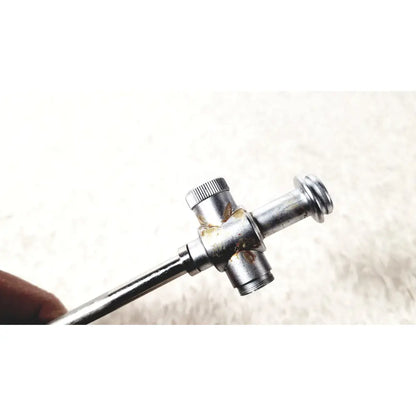Silver-colored metal laparoscopic obturator with knurled adjustment knob and rust spots for reuse medical laparoscopic instruments