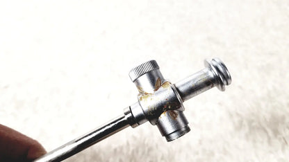 Silver-colored metal laparoscopic obturator with knurled adjustment knob and rust spots for reuse medical laparoscopic instruments