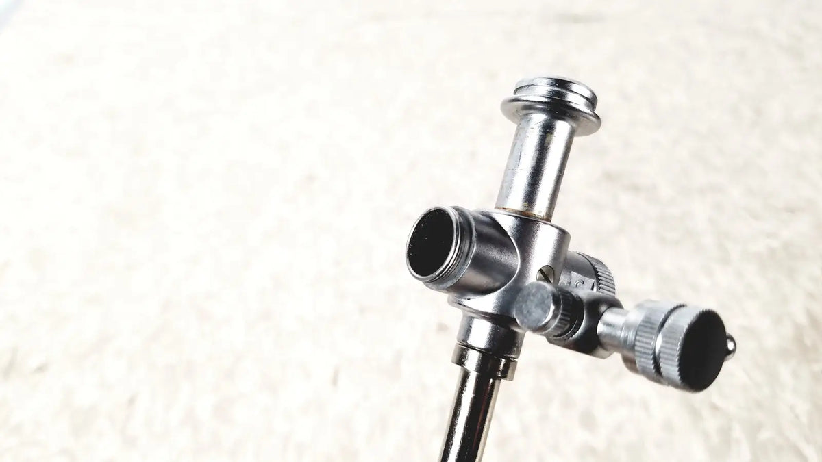 Silver metallic laparoscopic obturator tripod head with central column and adjustable arms for reuse medical laparoscopic instruments