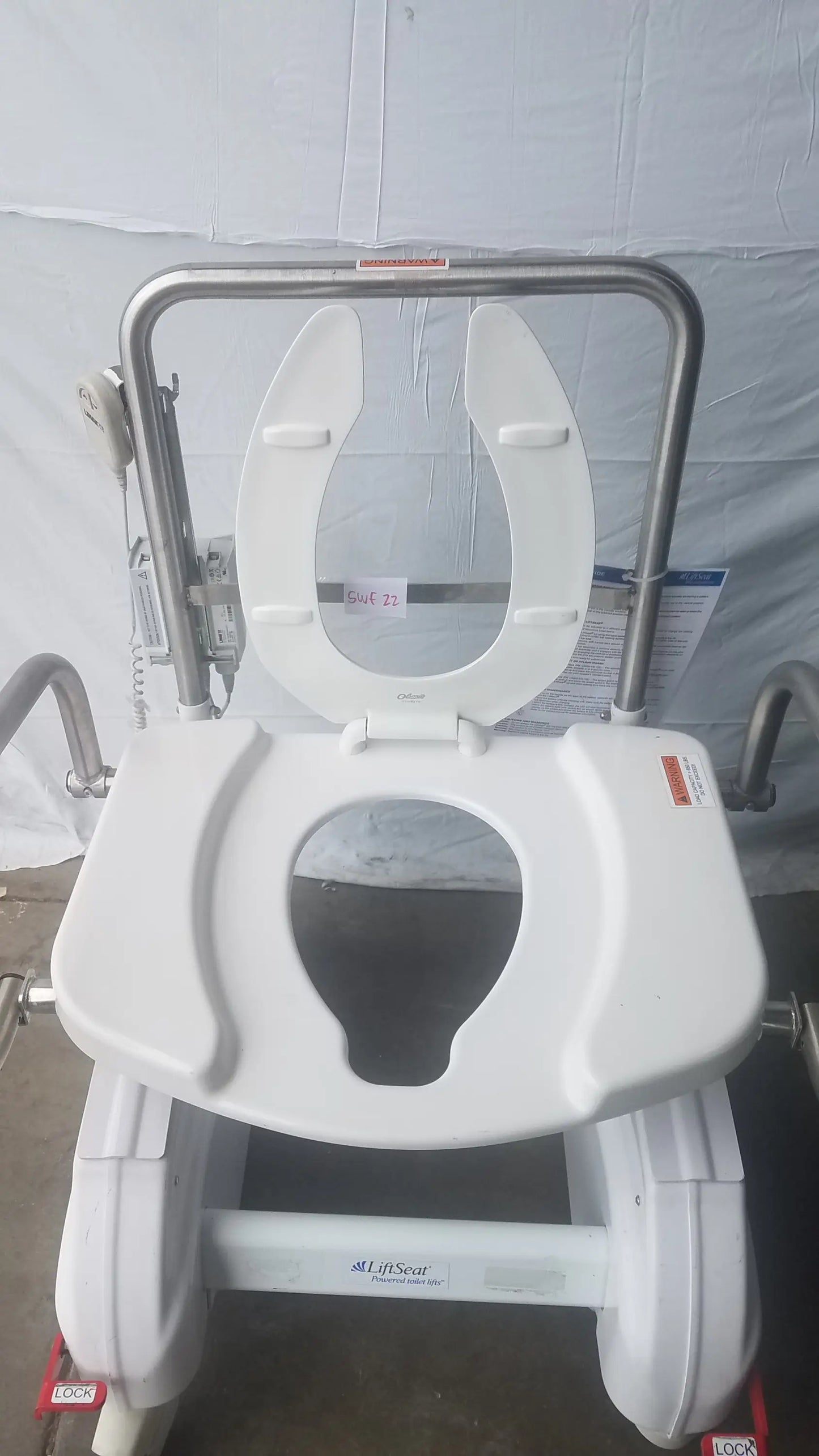 White plastic toilet seat with stainless steel frame and side rails on an adjustable bariatric power toilet lift