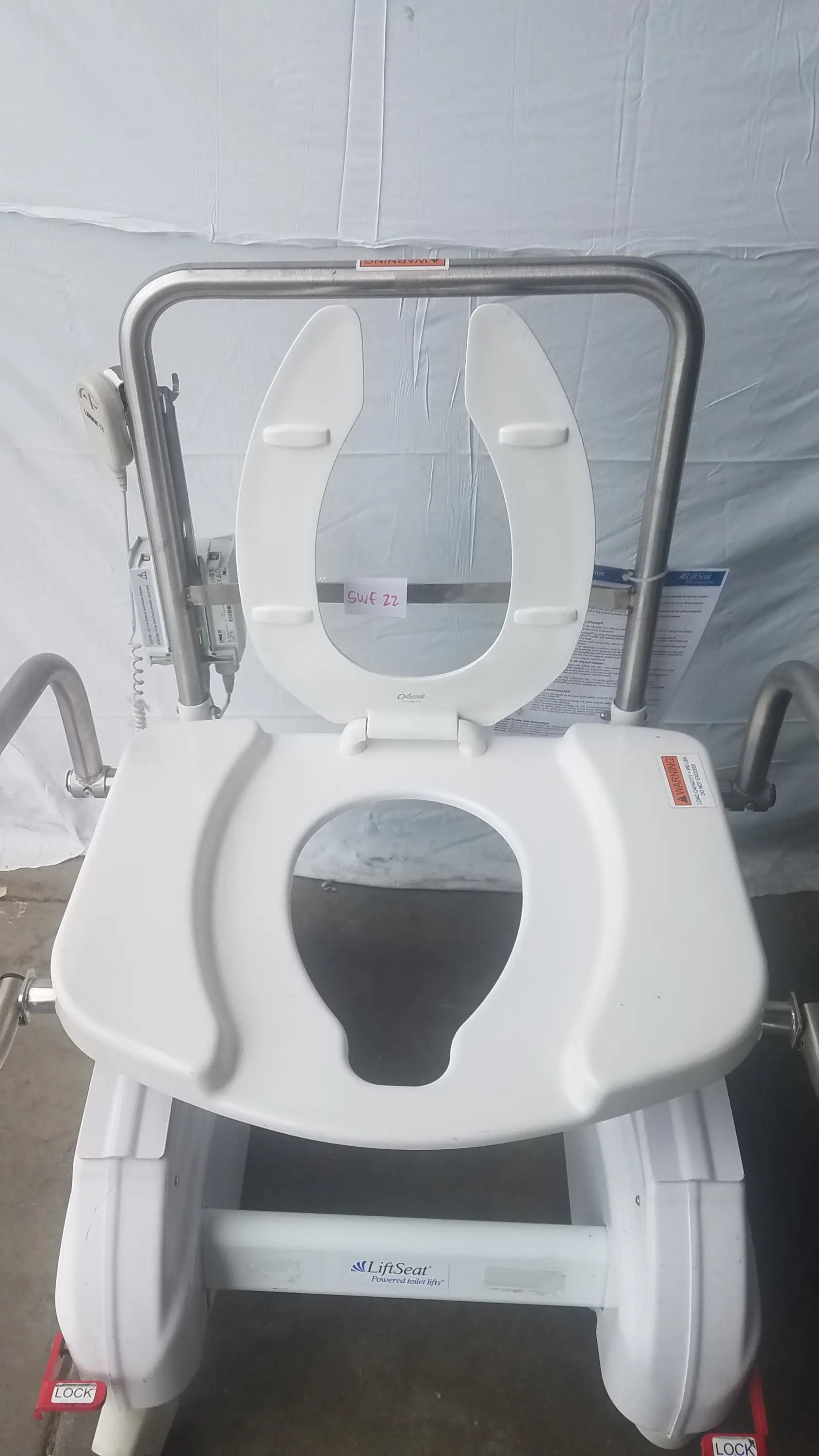 White plastic toilet seat with stainless steel frame and side rails on an adjustable bariatric power toilet lift