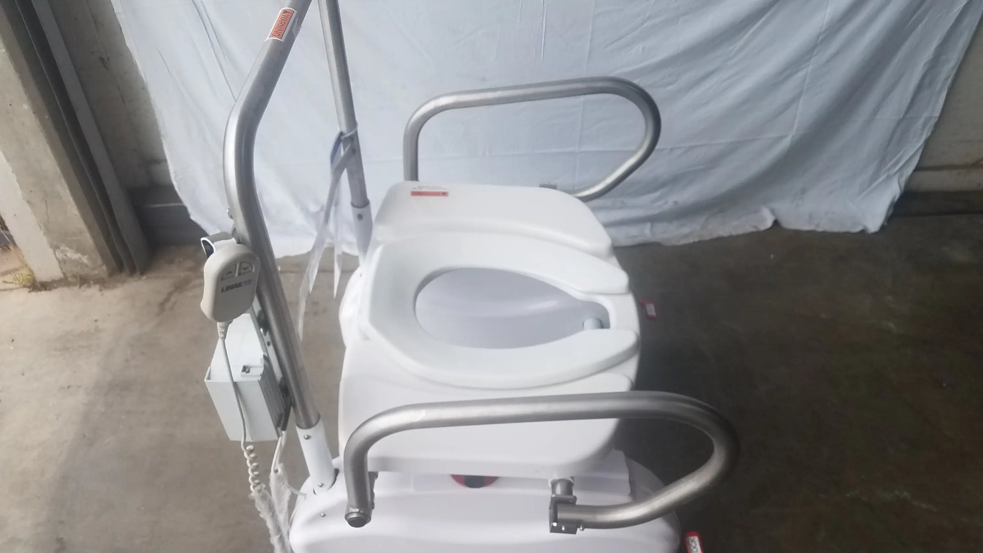 White LiftSeat LS600 bariatric power toilet lift with silver metal frame and handlebars for enhanced mobility