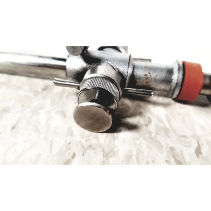 Silver metallic linvatec conmed hasson laparoscopic valve with textured knob and red rubber grip for surgical use