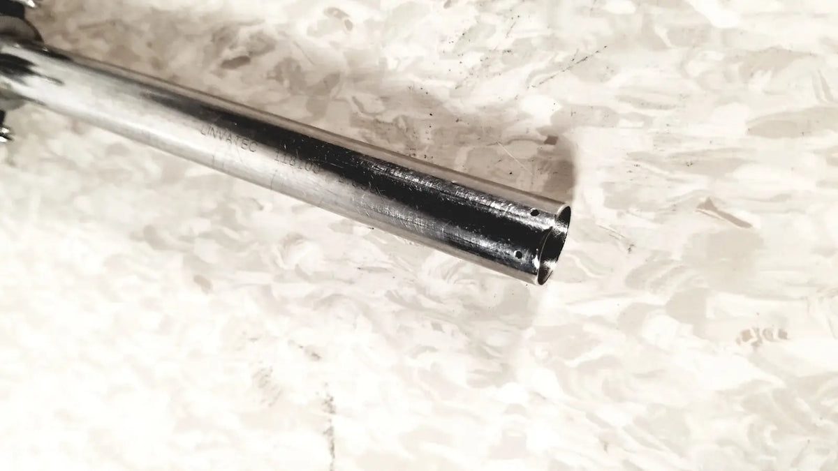 Shiny chrome-finished metal linvatec conmed laparoscopic valve with engraved markings and worn darkened interior for reuse medical use