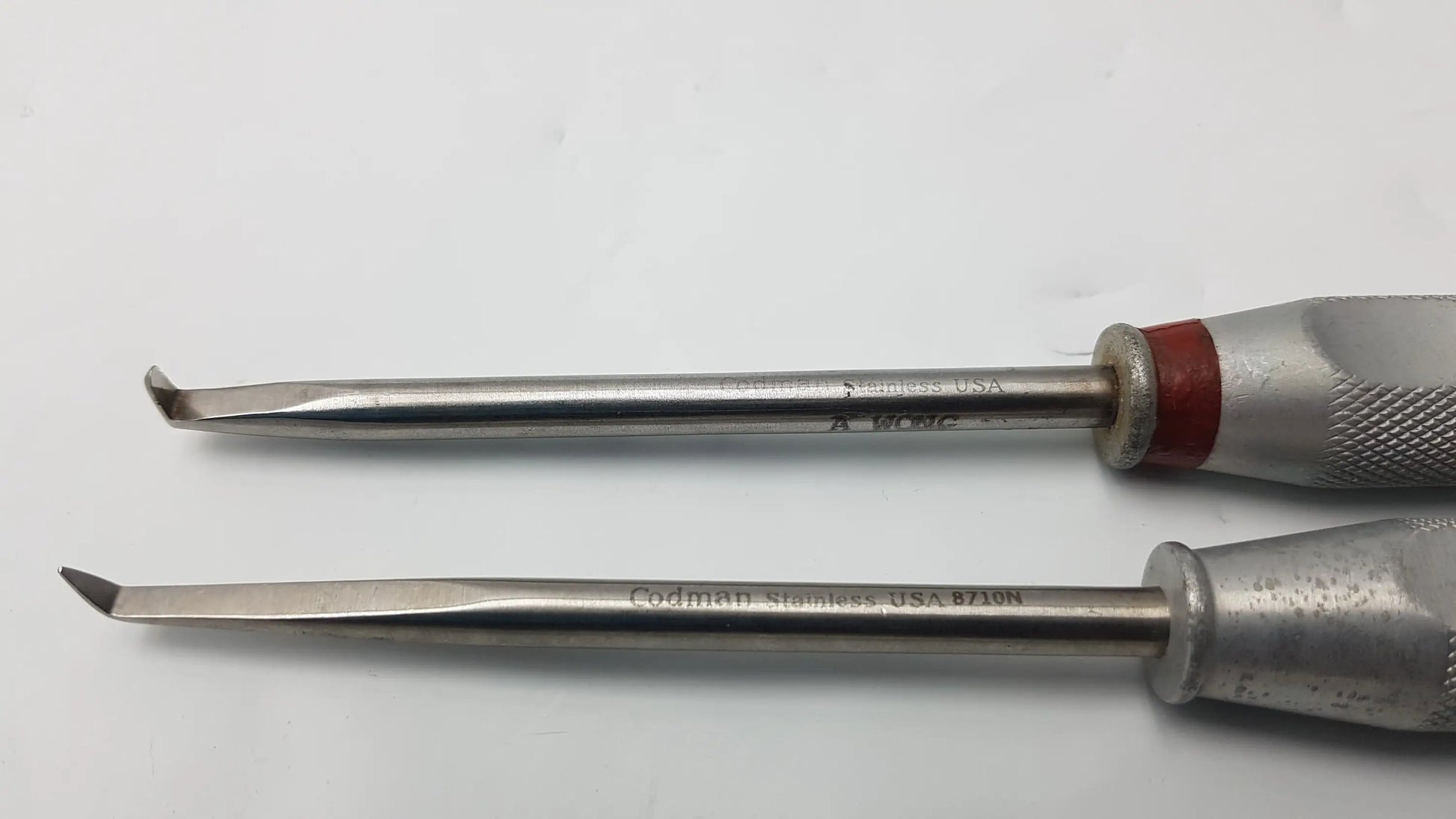 Two stainless steel codman 8710n osteophyte elevators with textured silver handles and red accents for orthopedic surgical use