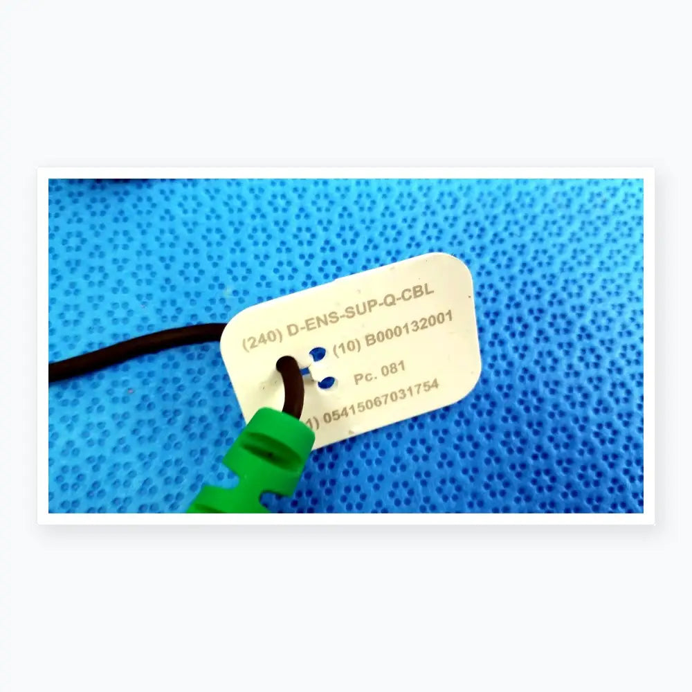 White rectangular label with serial numbers and green connector on black cable for reuse medical equipment use