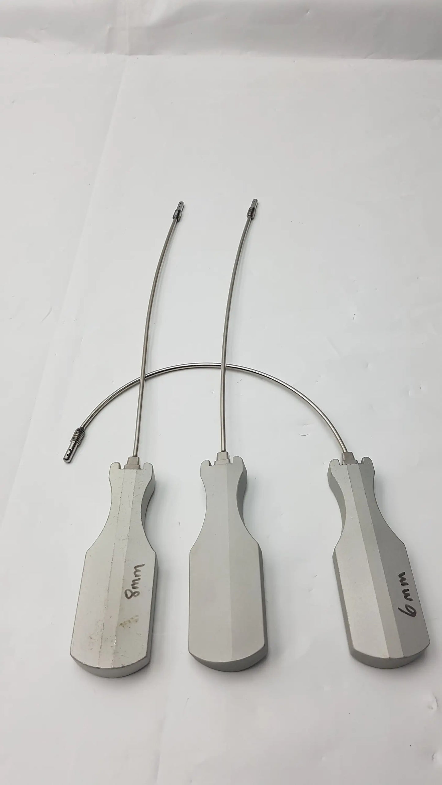Three metallic surgical retractors with ergonomic handles and labeled sizes for slight curve long and curve long use