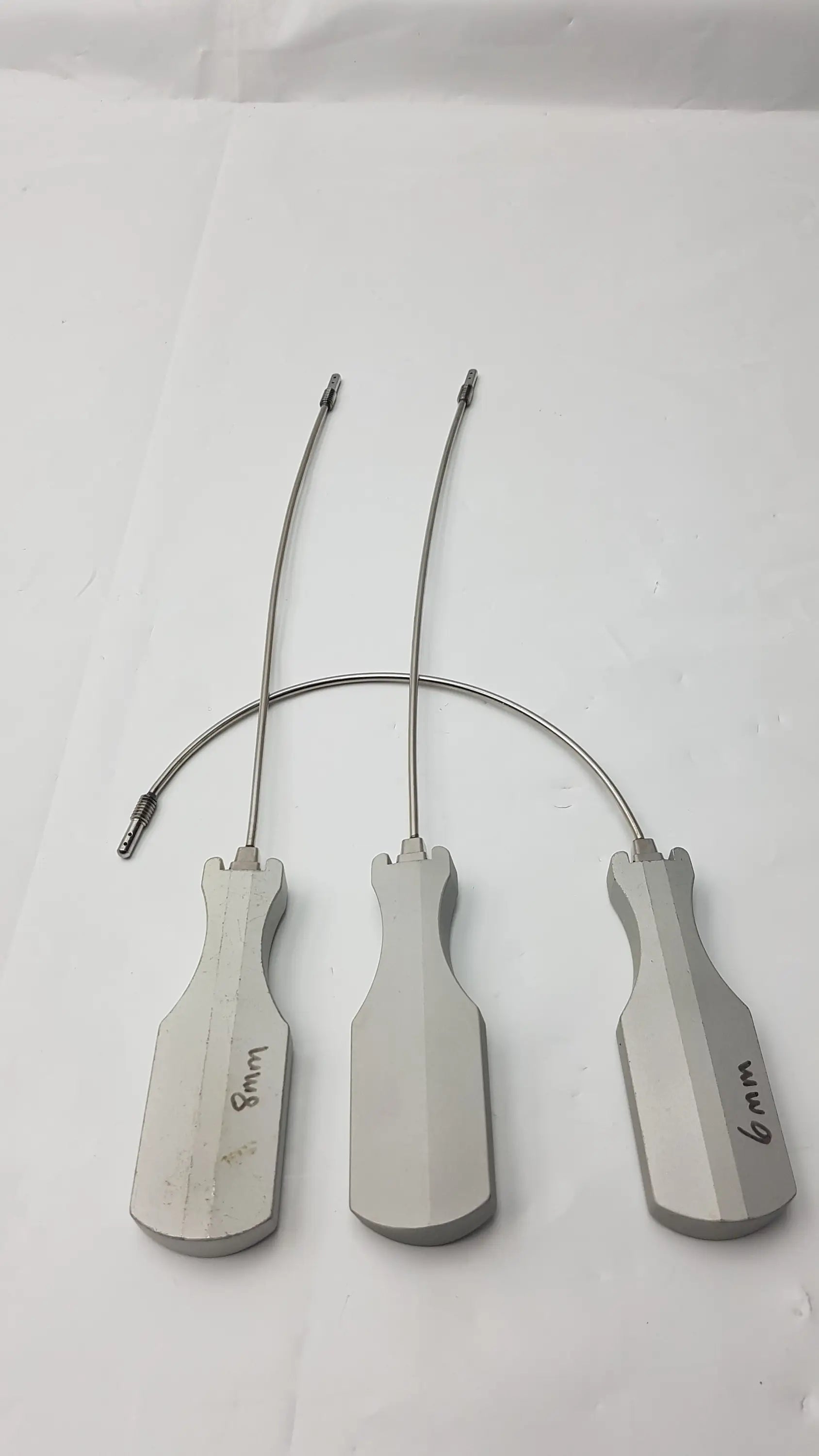 Three metallic surgical retractors with ergonomic handles and labeled sizes for slight curve long and curve long use