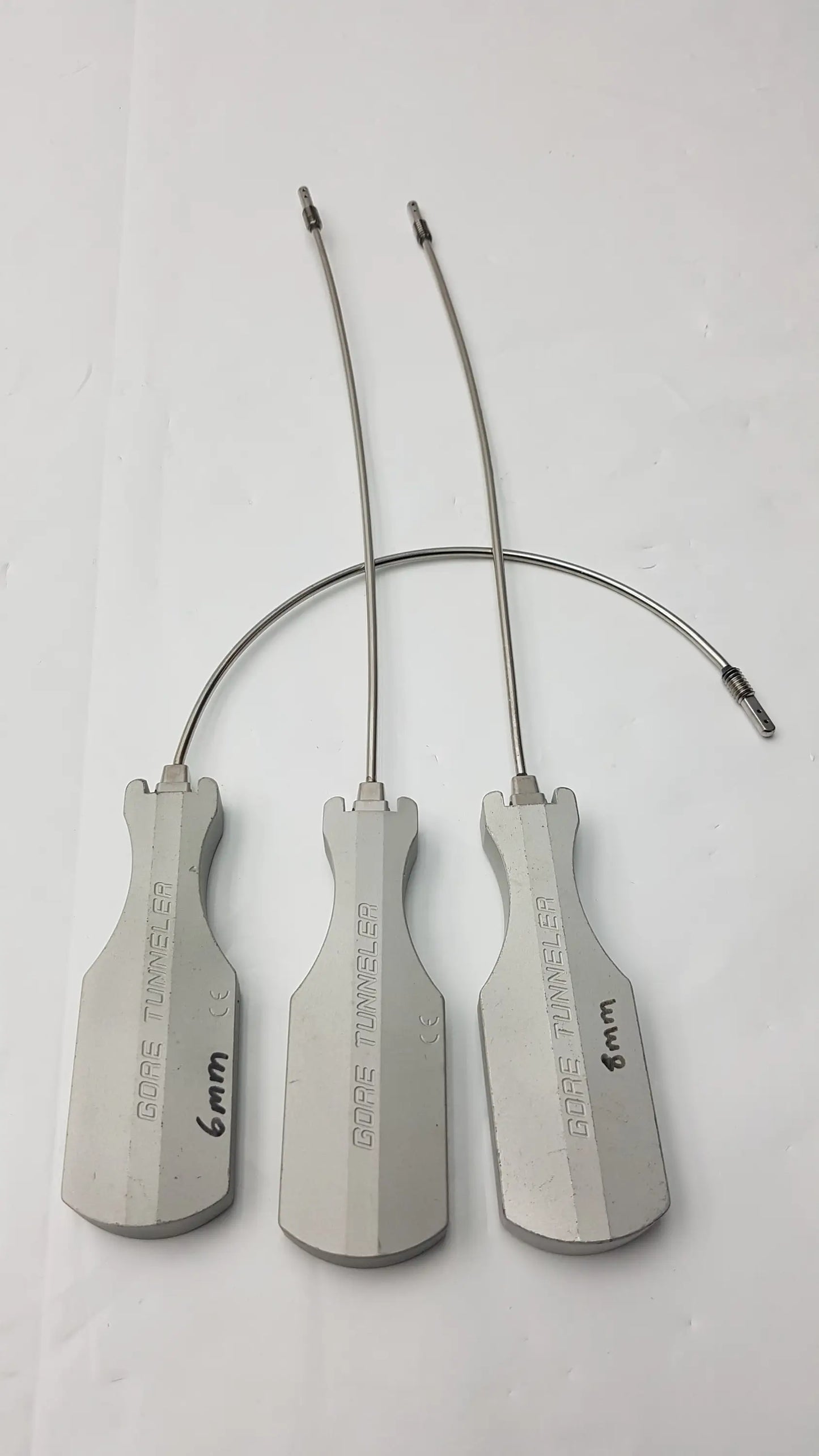 Three metallic gore tunneler surgical instruments with slight curve long and curve long wire handles and size markings