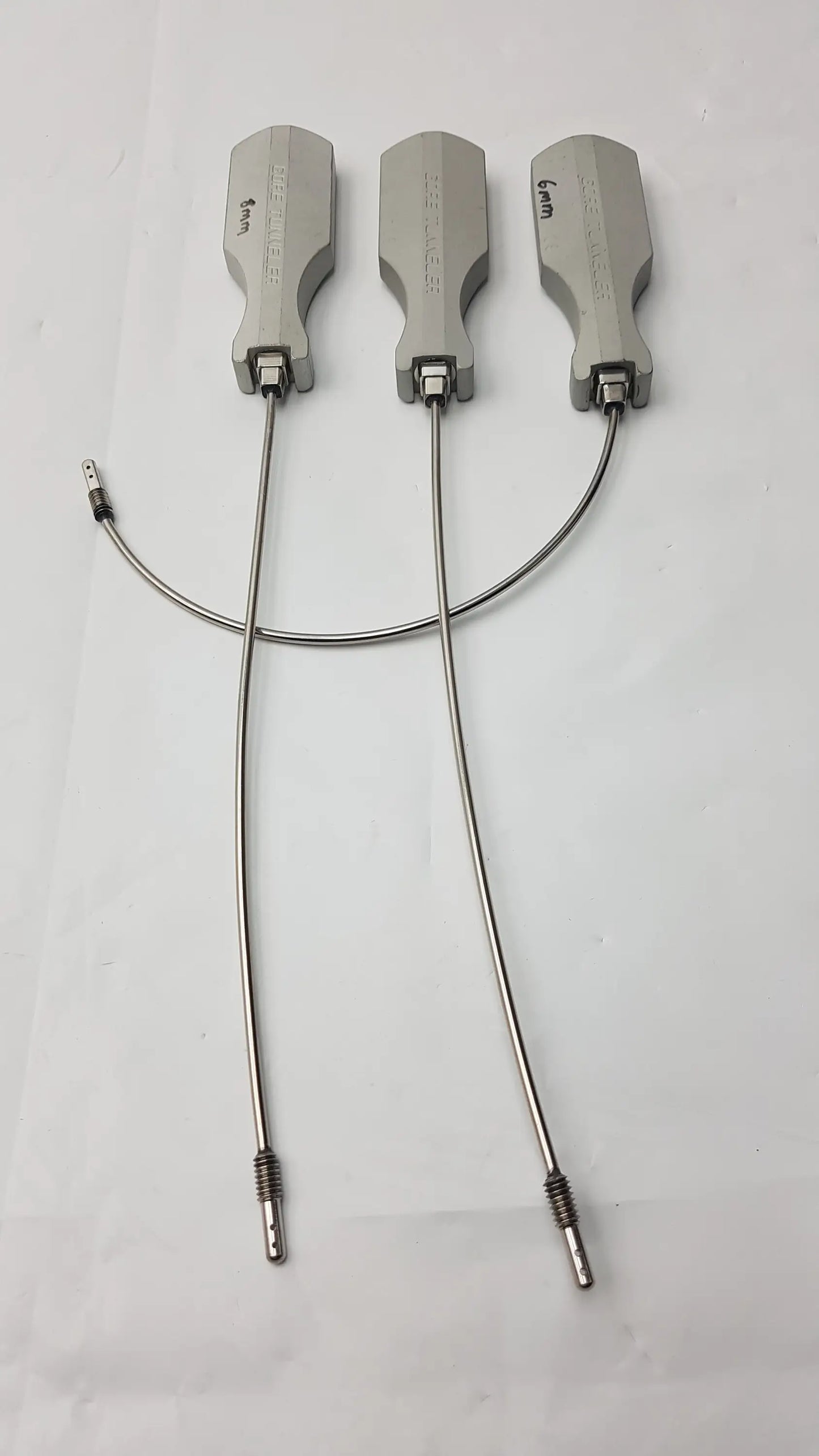 Three silver-colored gore tunneler surgical retractors with engraved markings and flexible metal arms slight curve long