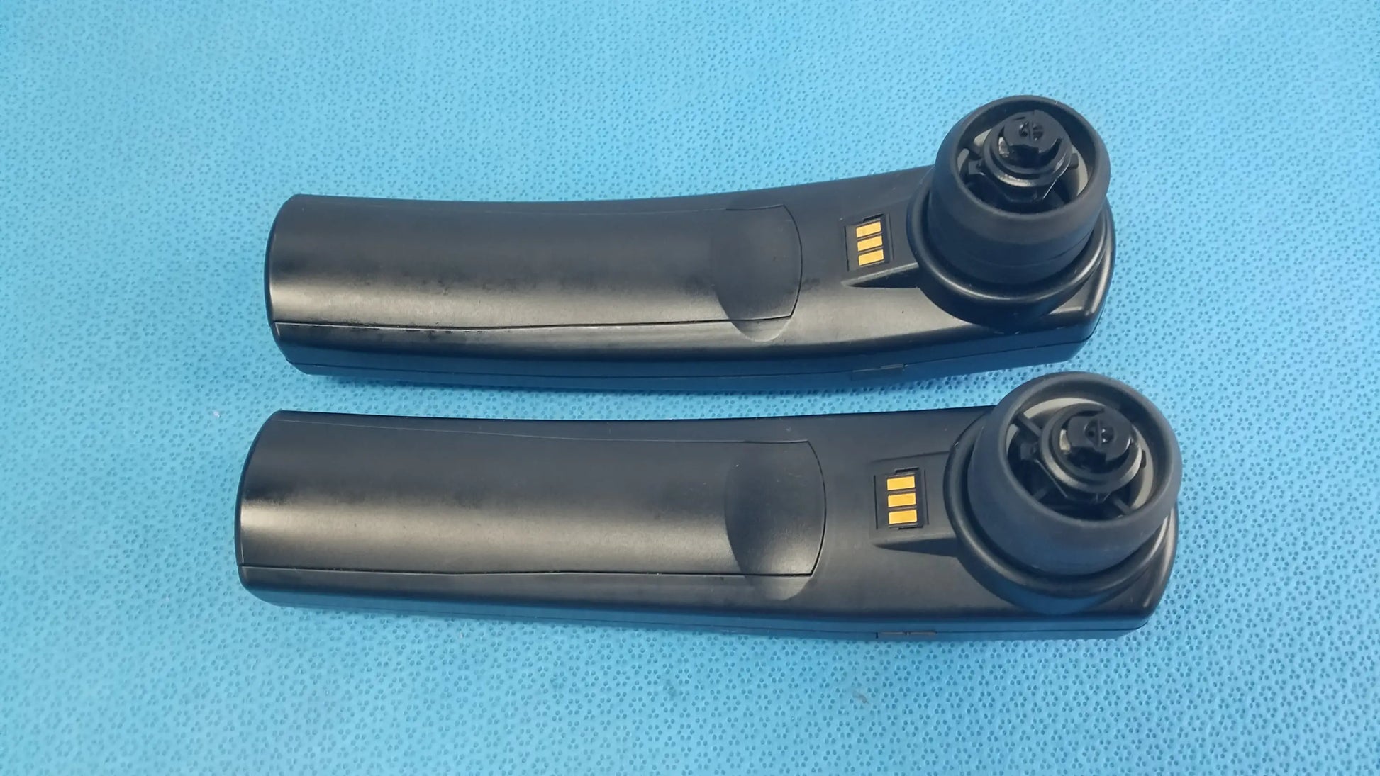 Black plastic car door handle remote key fob with gold contacts and circular button housing for handheld auditory use