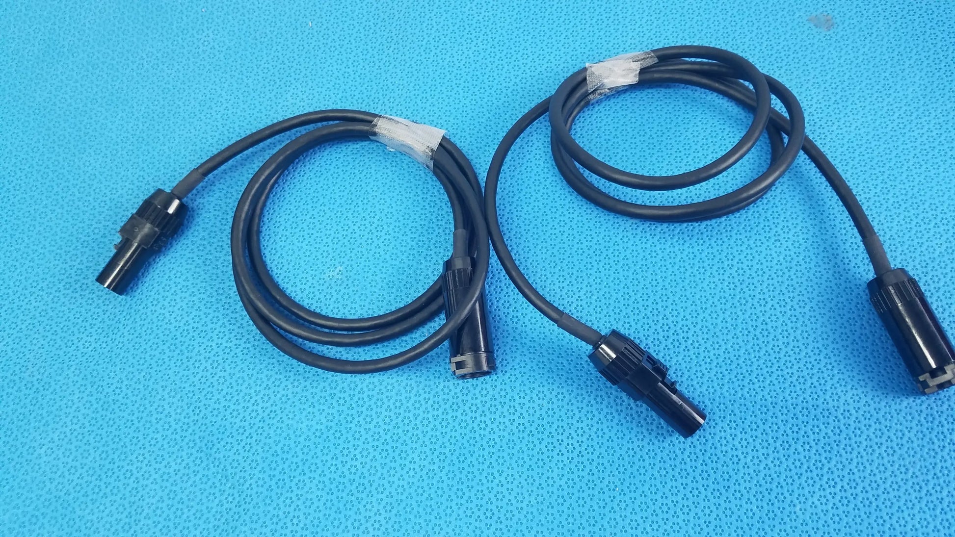 Lot of 3 black coiled mc4 solar connector extension cables with plastic connectors and white tape wraps for pv systems