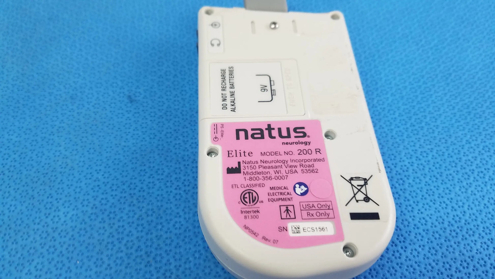 White plastic handheld doppler medical equipment labeled natus neurology elite model 200r with pink sticker and regulatory markings