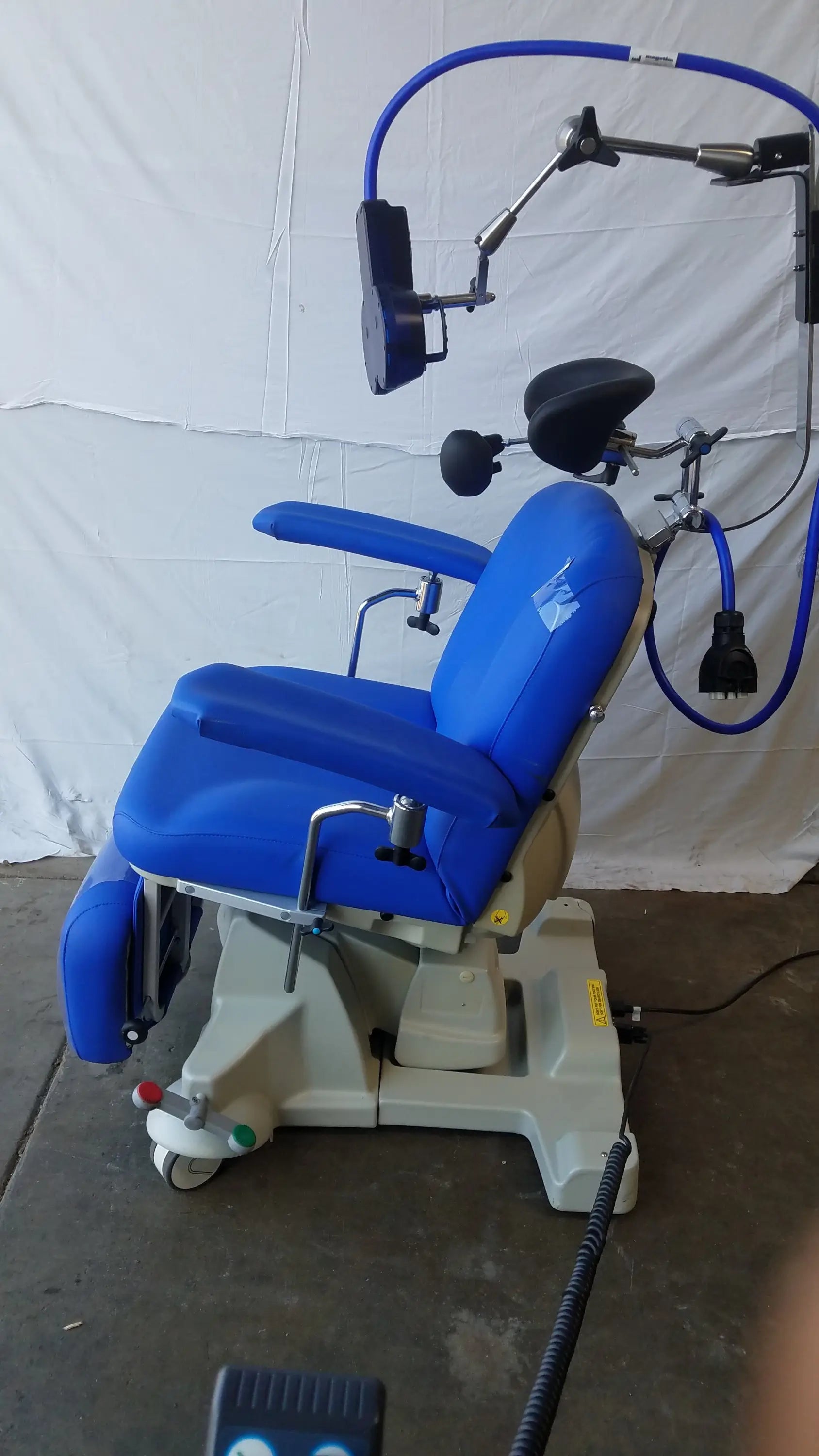 Blue magstim tms therapy chair with articulating arm, stimulation coil, adjustable armrests, and headlight attachment