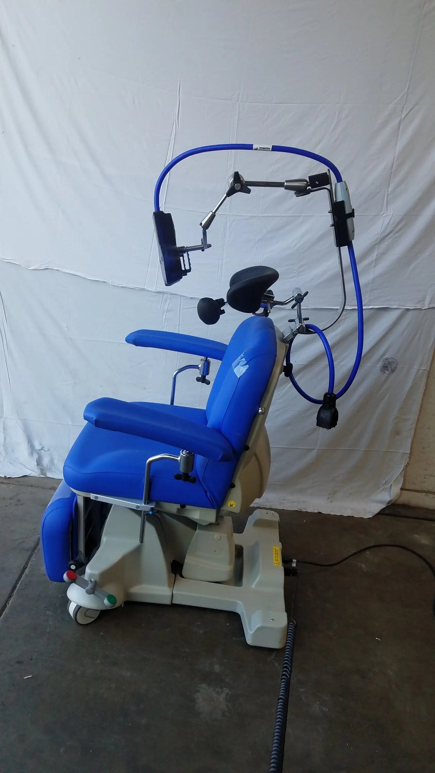 Blue Magstim therapy chair with adjustable headrest and articulating arm holding stimulation coil and monitor