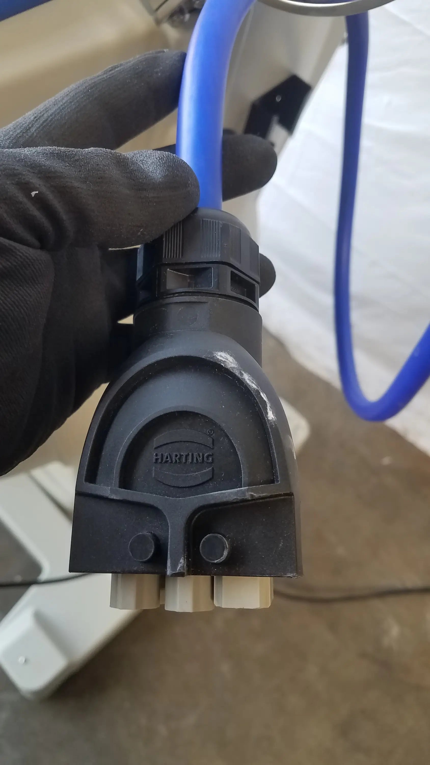 Black plastic harting industrial connector with blue tubing attached to magstim tms therapy chair articulating arm stimulation coil